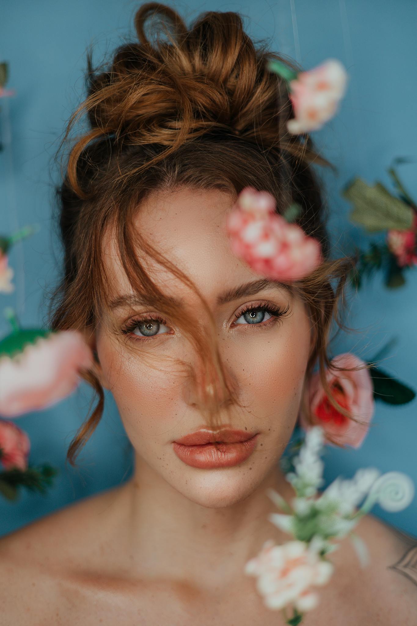 Artistic portrait of woman with flowers on blue background.