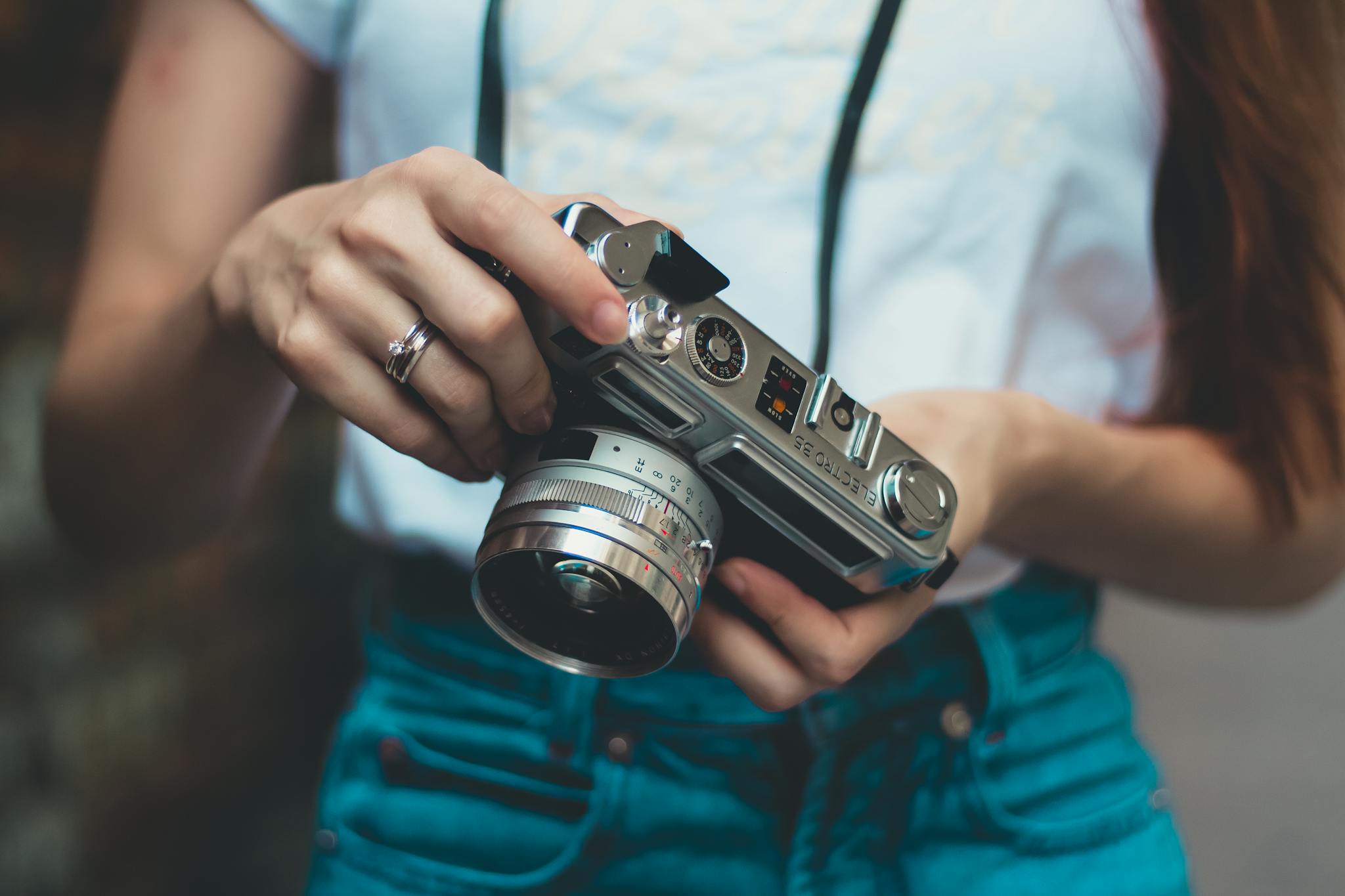 Young woman holding a vintage camera outdoors, showcasing retro photography equipment.